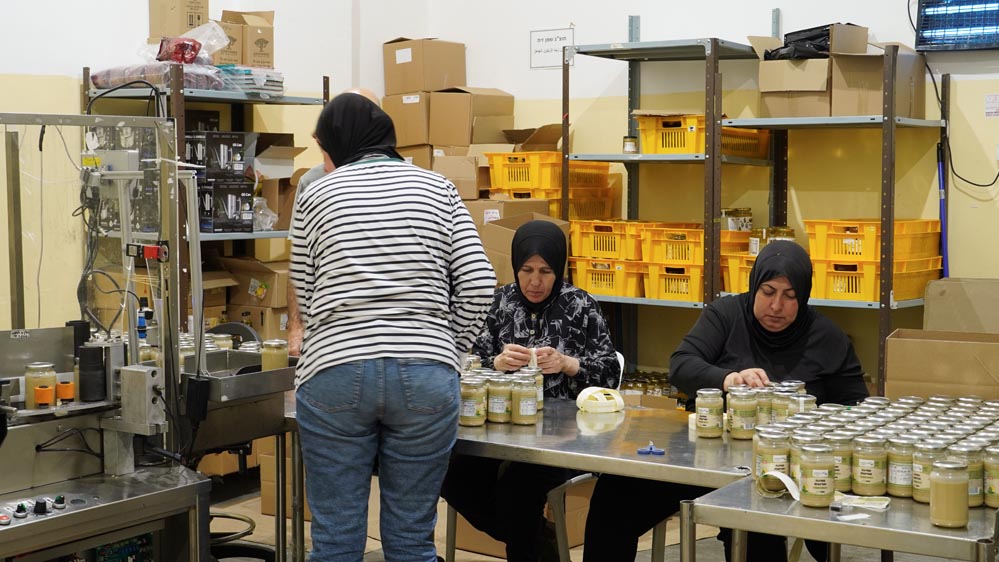 Mujeres árabes y judías colaborando juntas en el taller de la empresa social Sindyanna de Galilea, promoviendo el comercio justo y la coexistencia.
